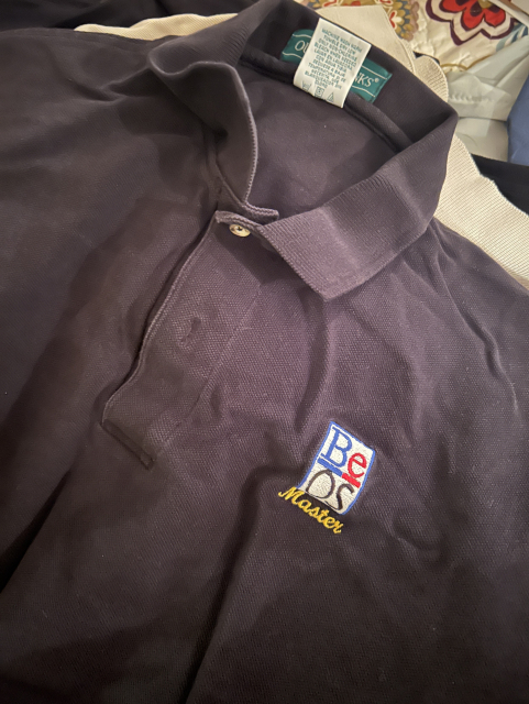 Picture of a black polo shirt with the logo BeOS Master on it.