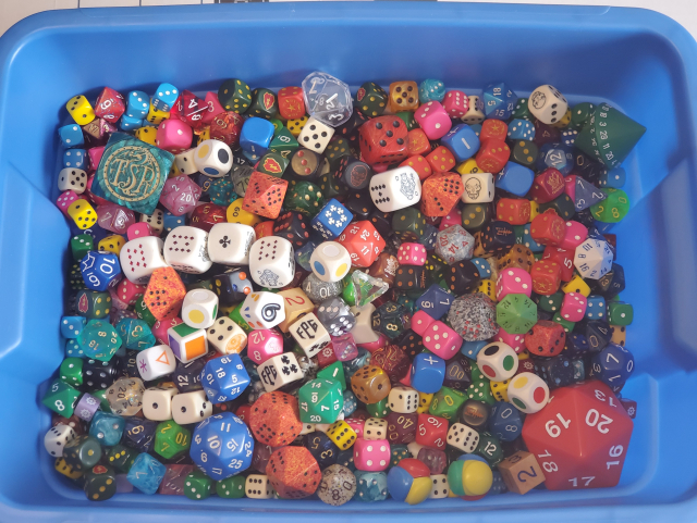 A tub full of dice of various shapes, colours and sizes.