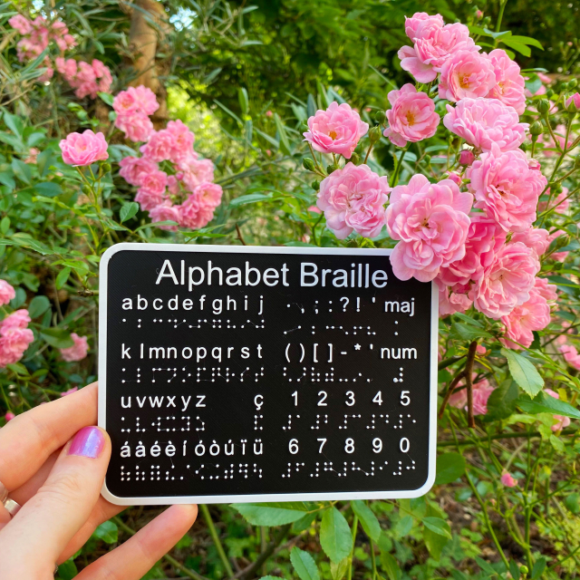 Planche de bioplastique noire sur laquelle est imprimé en blanc l'alphabet braille, certains caractères accentués, d’autres signes micro-typographiques, ainsi que des chiffres.