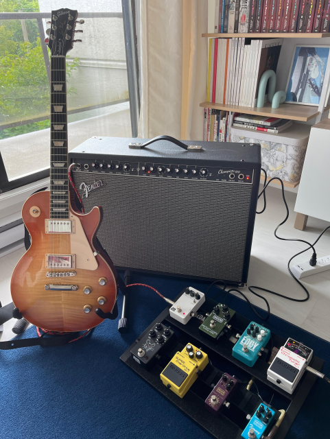 Gibson led Paul guitar in front of a Fender amp and a pedal board with guitar pedals 
