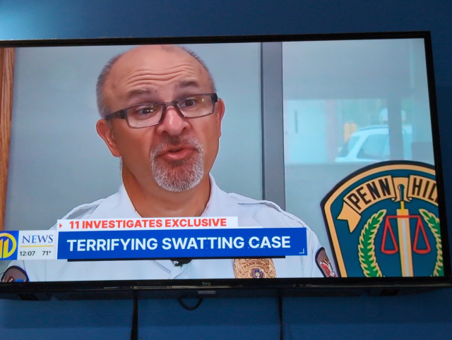 A photo of a TV screen showing a cop talking with the caption "TERRIFYING SWATTING CASE".