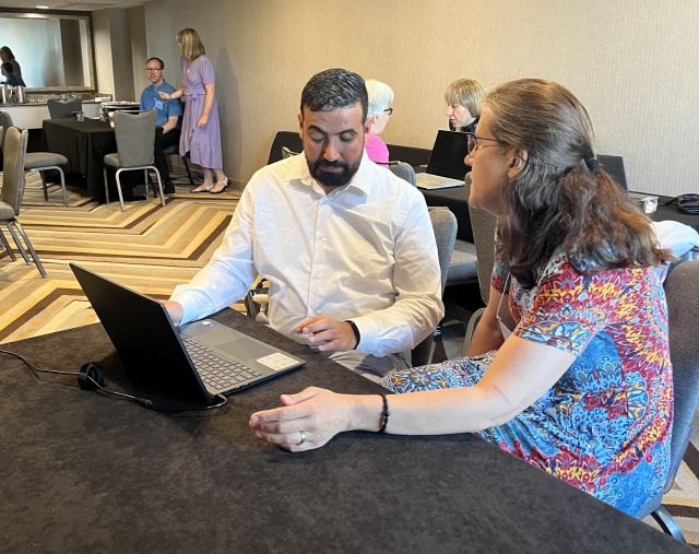 Mohammed Laachir sitting at a table with a female customer in the JAWS AI Training Suite at ACB.