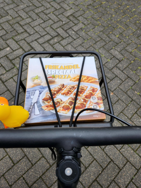 Box of frikandel speciaal pizza sitting in bicycle front carrier