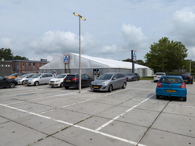 A temporary store of Aldi with a temporary parking lot in front of it.