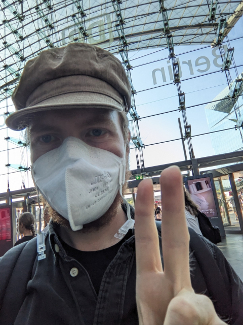 I make a "peace" hand gesture towards the camera in Berlin Central Station.