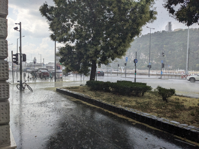 Rainy street, with a hill in the background.