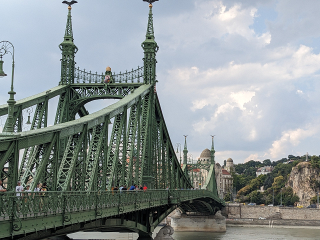 A steel bridge spanning a wide river. A cliff in the background.