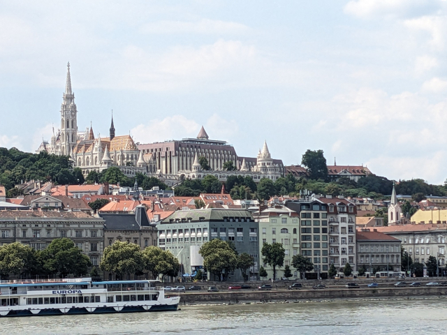 A fancy white church on a hill over a river.