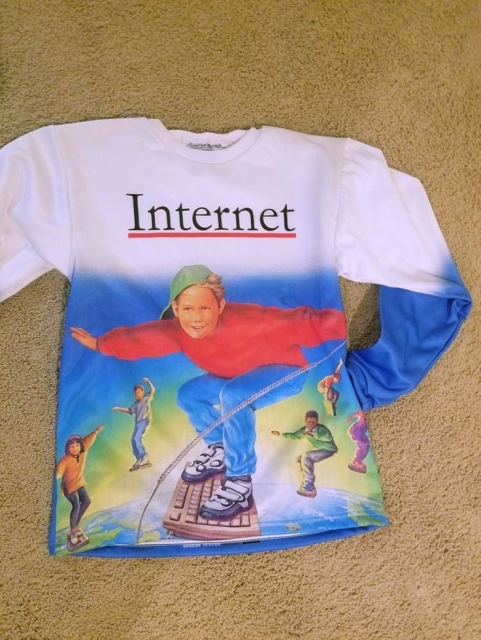 Foto eines bedruckten Sweatshirts, auf dem "Internet" steht. Darunter, vor einem bunten Hintergrund, surfen Kinder auf Tastaturen.