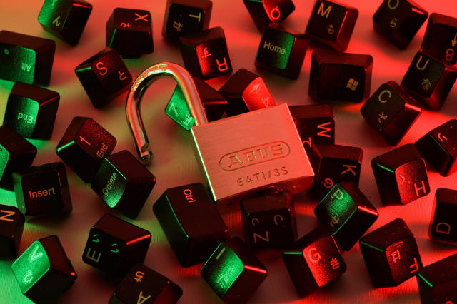 An open padlock resting on top of a pile of keyboard keys.