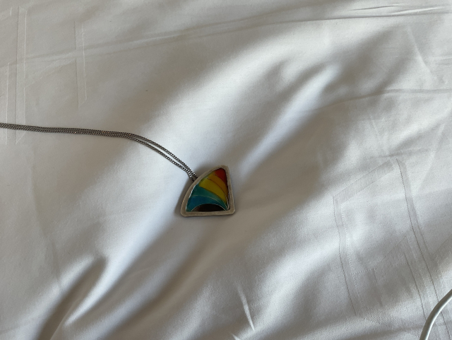 A triangular rainbow necklace, with the colors of the rainbow in it.