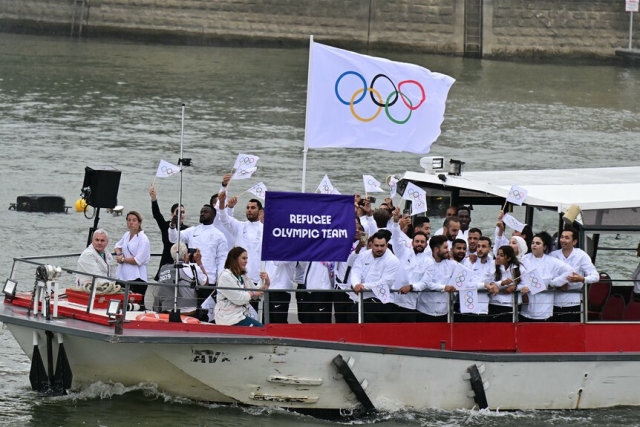 Refugee Olympic Team waving flags in a boat at the Paris Olympic Games Opening Ceremony