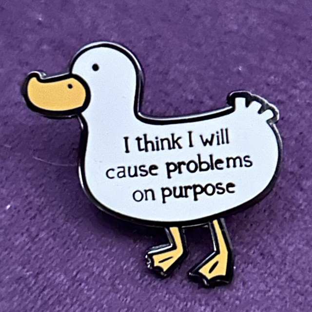 A white duck-shaped pin with the text "I think I will cause problems on purpose" on a purple background.