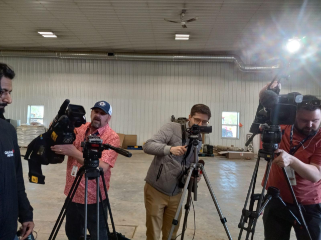 3 journalists setting up TV cameras and lights facing toward me, there were 2 more off to the left with mics, (and off to the right is the next picture).  We're all inside a large metal farm shop building.