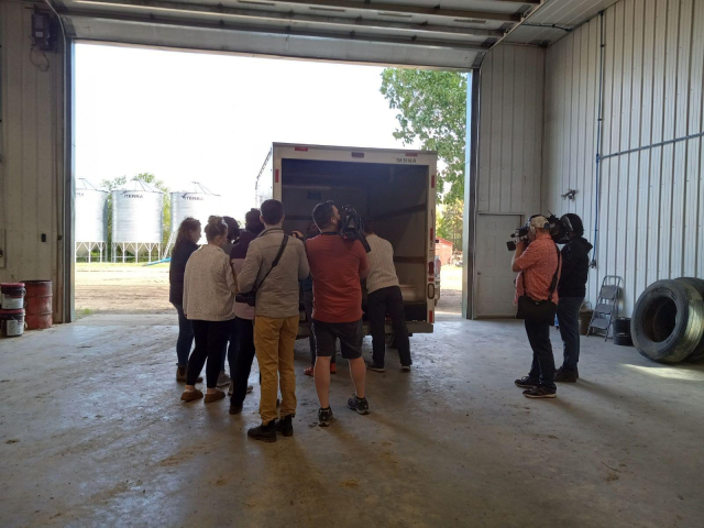 A whole flock of reporters with cameras and mics clustered around the back of a Uhaul as the 2 engineers load the space junk into the back