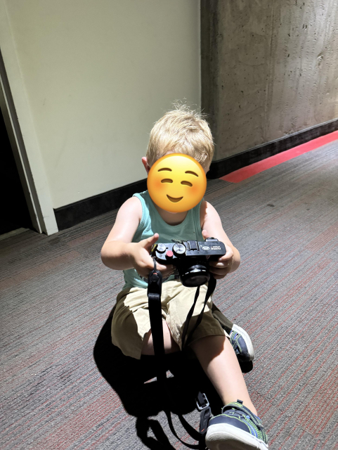 Child playing with a Fujifilm X100VI camera in a hallway