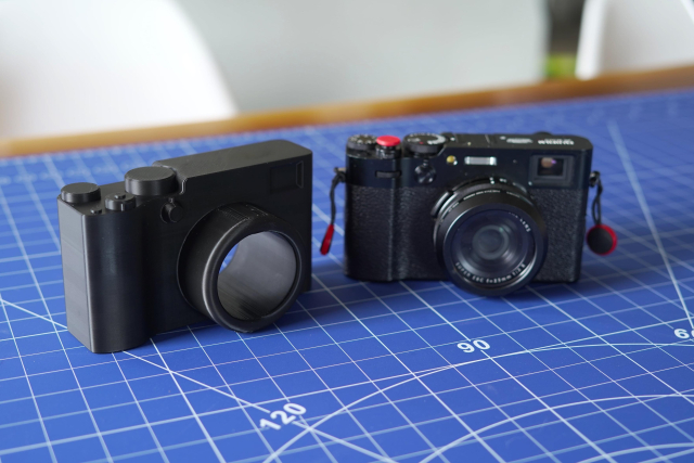 A 3D printable replica of the X100VI next to the real X100VI on a blue project mat