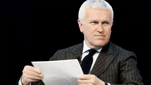 A picture of Italian journalist Maurizio Belpietro. A middle-aged white man with short, almost white hair and a dark grey "gessato" suite, a white shirt and a black tie.