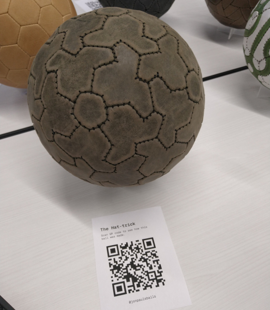 Photo of a brown soccer ball made of hat tiles and pentagons. Contains QR code for more info