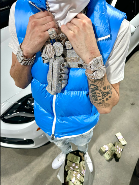 A partial selfie Punchmade Dev posted to his Xitter account shows him dangling both sets of fingers from a number of enormous and gaudy medallions and thick gold chains. Among the medallions are a gold and diamond covered bitcoin, and a diamond covered fully functional credit card skimming device with a hand underneath it, also in diamonds. He is standing next to a white vehicle and over bags of bundled cash. On his wrists are diamond covered watches. In some of his twitter videos, he shows the diamonds are real and supposedly of high quality, using some type of electronic device.