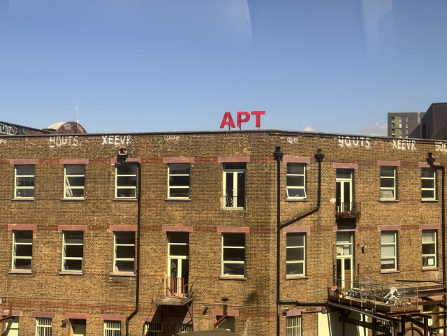 A nondescript and somewhat derelict building with big red letters saying “APT” on the roof