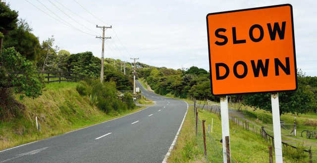 an empty road with a road sign saying "slow down"