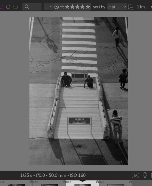 Crop of screenshot a Darktable photo editor, centered around the picture being edited.

A black and white photo taken from above. 

In the middle of the frame, two people climbing the stairs on their knees. Going from the stairs toward the top, a cross walk on cracked asphalt.

To the right people standing on to of the stairs, and other people walking away in the top right quarter of the frame. Shadows are cast toward the bottom right.