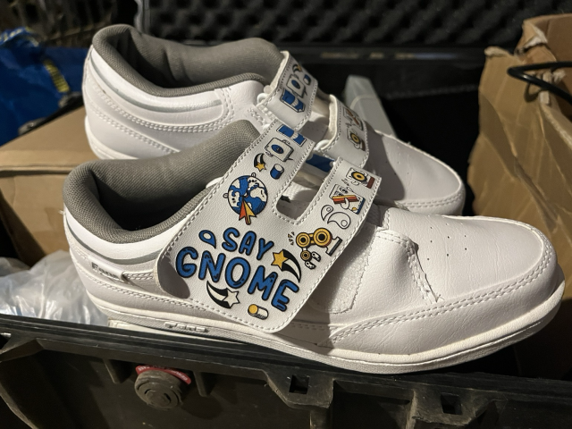 A pair of white shoes with GNOME artwork printed on it, There are drawings of gnome app logos.