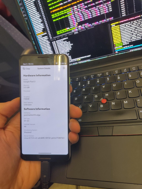 the pixel 3 in my hand in front of my laptop with kernel sources open. the pixel 3 screen shows the GNOME settings hardware info page, it's running linux 6.11-rc2