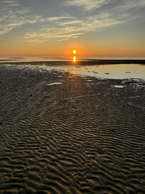 Sunset over water with sand foreground