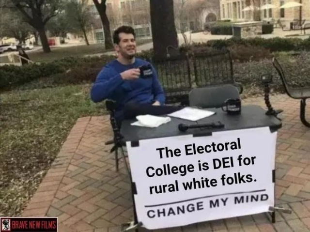 Image of a man holding a coffee cup sitting behind a desk in a park with a sign on the front of the desk that says:
The Electoral College is DEI for rural white folks.
Change my mind