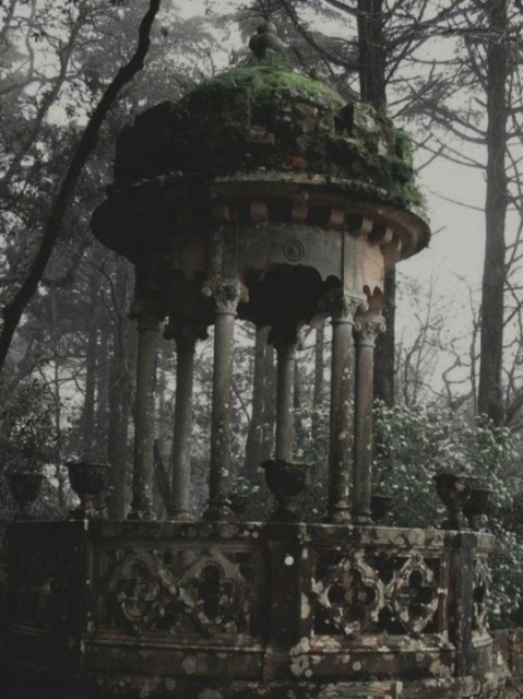 This is a folly in the edge of the property, it has very Greek/Roman energy with pillars, and beautiful ornate roof and fence around it with empty planters 