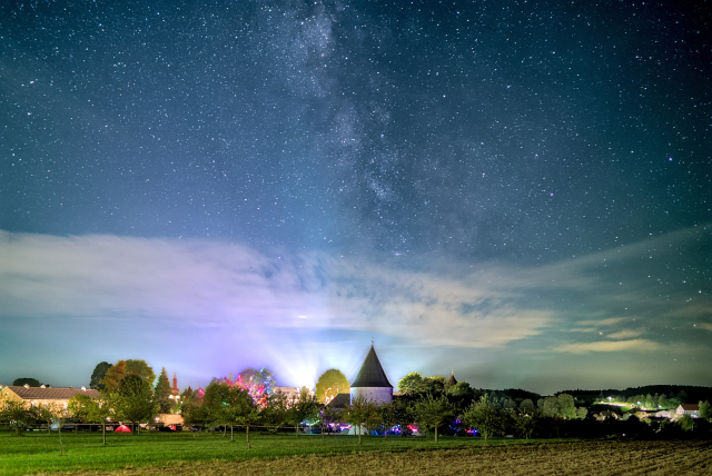 Nächtliche Foto der Milchstraße über dem Schloss Ottenschlag, weiches hell beleuchtet ist, will dort gerade Hack ma's Castle stattfindet.