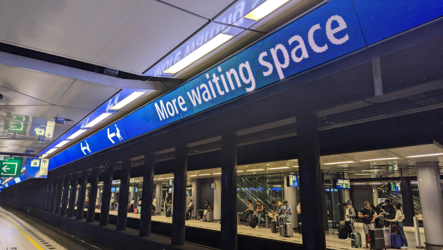 A view of an underground platform. Above the track, there is LED signage saying More waiting space.