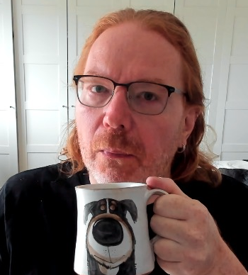 Chris Heilmann blowing on a huge coffee mug with the face of a dog on it.