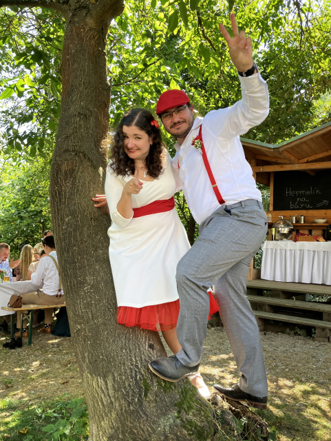 Me and Anna at the swing style wedding dress. I have a white shirt, grey trousers, red braces and red cloth cap. Anna has a white dress with red belt and red slip.