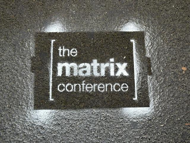 A sign spray painted on the ground reading “the matrix conference”