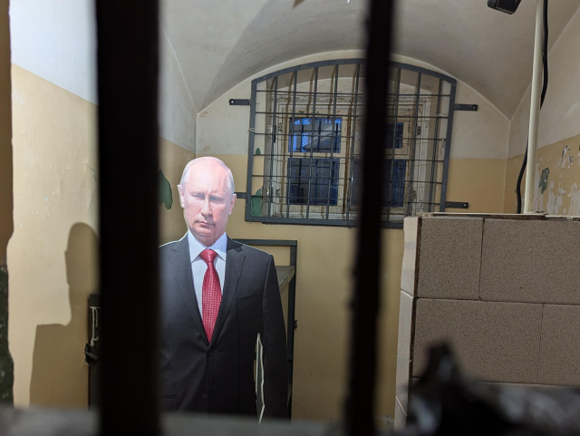 A prison cell with a life-size cardboard statue of Vladimir Putin behind the bars.