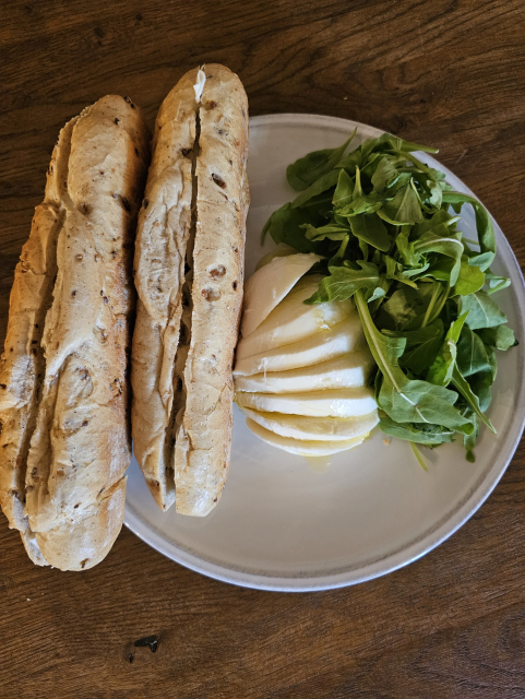 rožky so syrom, mozzarella s olivovým olejom a rukolou na bielom tanieri 