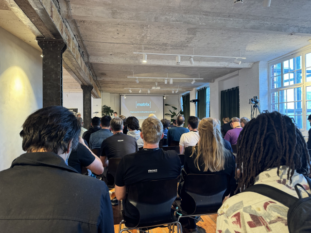 A picture of a room full of people watching a speaker wrap up the conference