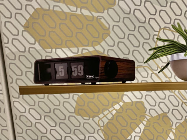 A picture of a bedside table radio clock showing a time of 5:59.