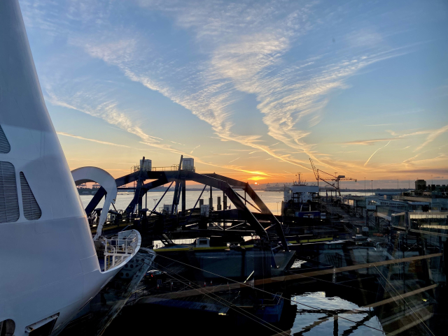 View across the loading bridge (the bow of the ferry is barely in the left) and the port’s waters towards the horizon where the sun is starting to rise.