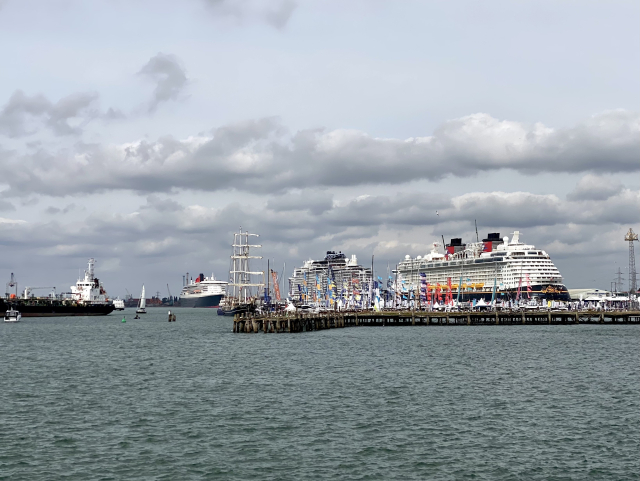 View over the harbour waters. We can see three big cruise ships moored one after another. There’s also a tall sailing ship moored in between, looking very tiny. 