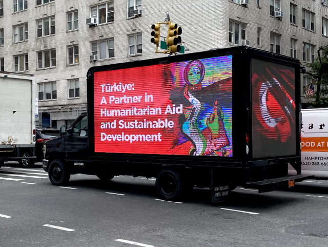 A box truck with its sides covered in large LED displays. The one on the side reads: “Türkiye: A Partner in Humanitarian Aid and Sustainable Development.”