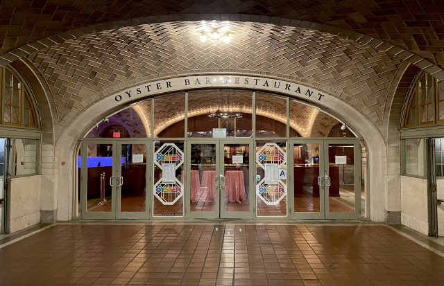 An arched underground entrance way with the lettering “Oyster Bar Restaurant” over the doors.