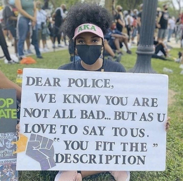 Black female protestor holds sign that reads: Dear Police, we know you are not all bad, but as you love to say to us, "you fit the description."