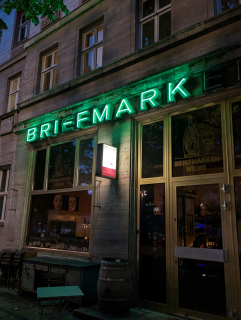 Eine Defekte Neonreklame zeigt nur noch einen Teil des Wortes Briefmark an, sodass der Schriftzug Bri-FMark in großen grünen Lettern über der Tür steht 