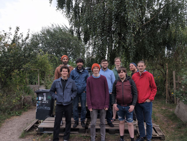 Group photo of a dozen or so hackers in front of some trees.