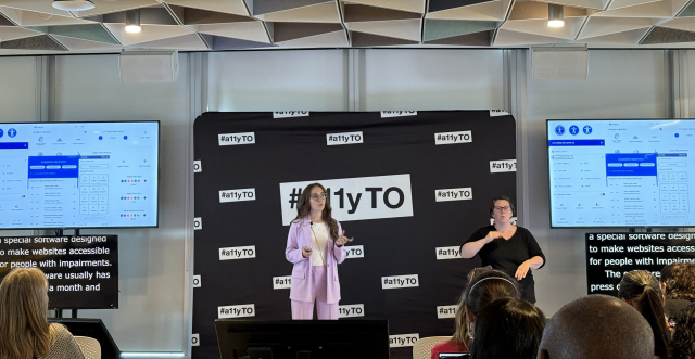 Daniela in front of the a11yTO sign with slides left and right, screens with live captions and a sign language interpreter