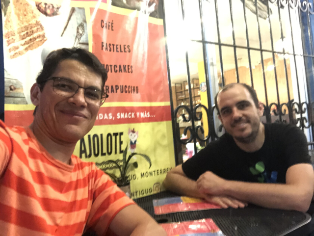 Two hacker dudes seated at a table, taking a rest from walking around Monterrey.